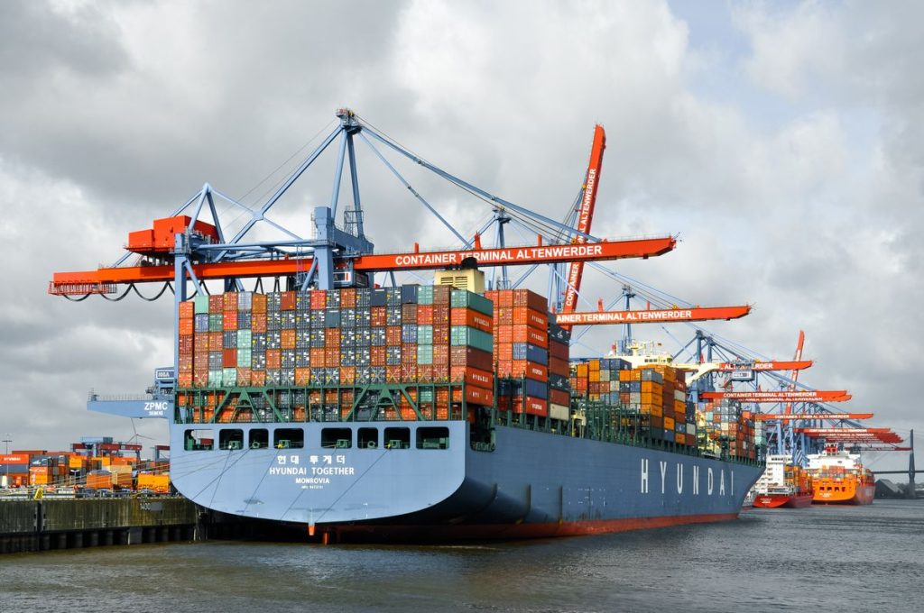 Loaded container ship docked under cranes at a port terminal