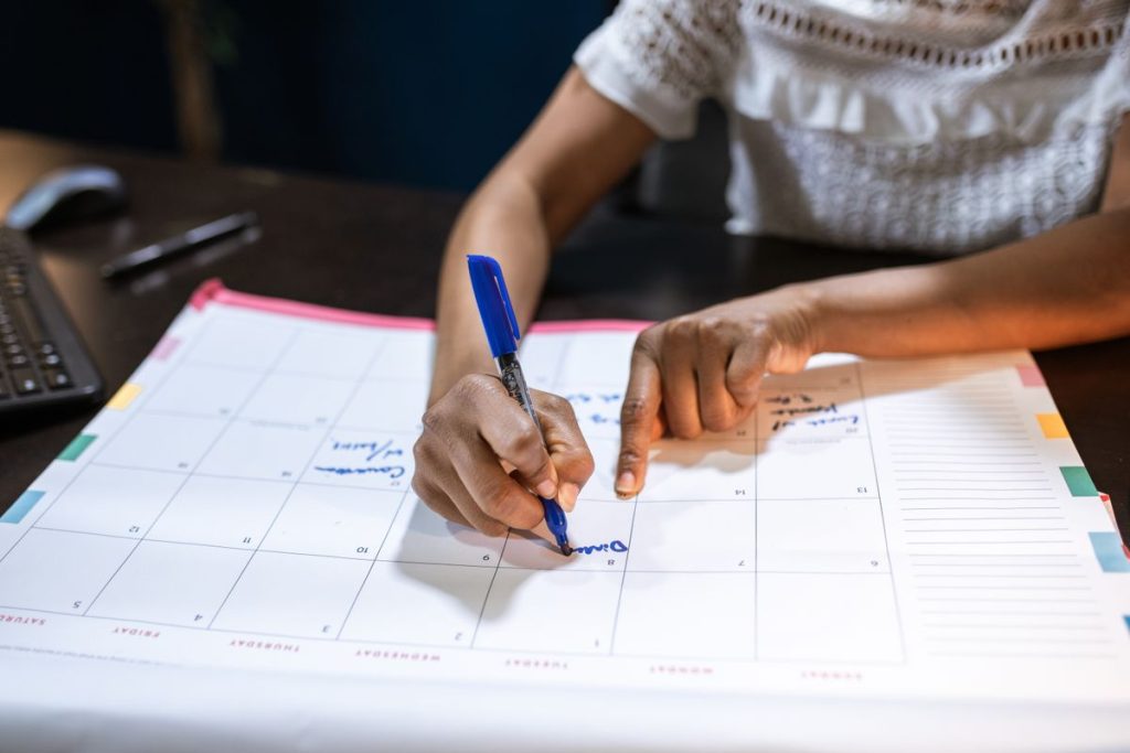Hands annotating a monthly editorial calendar with a pen