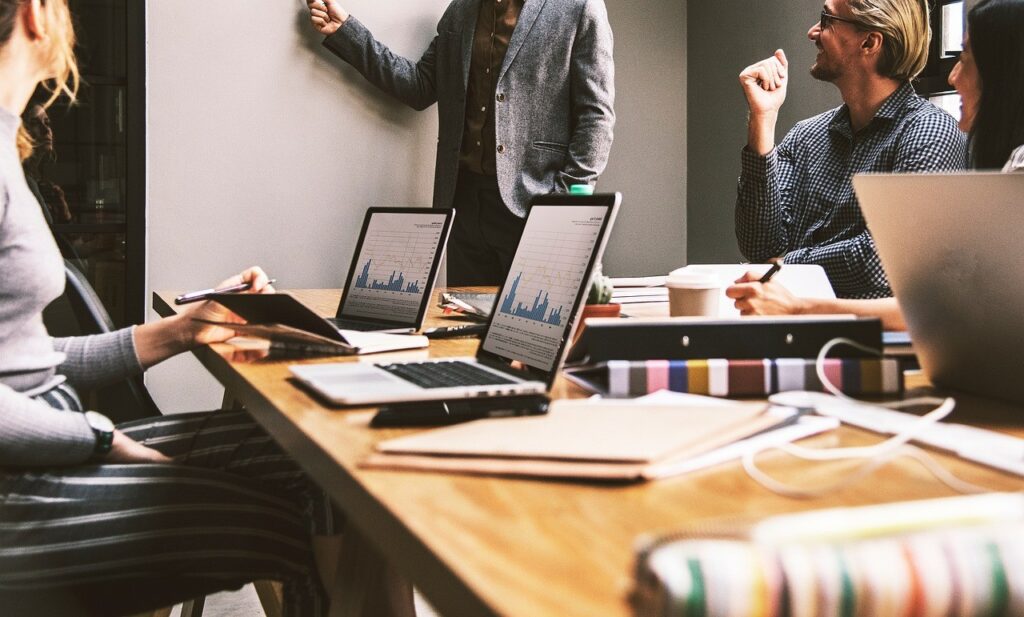 Une équipe se réunit autour d'une table de travail avec des ordinateurs portables, dans un bureau lumineux