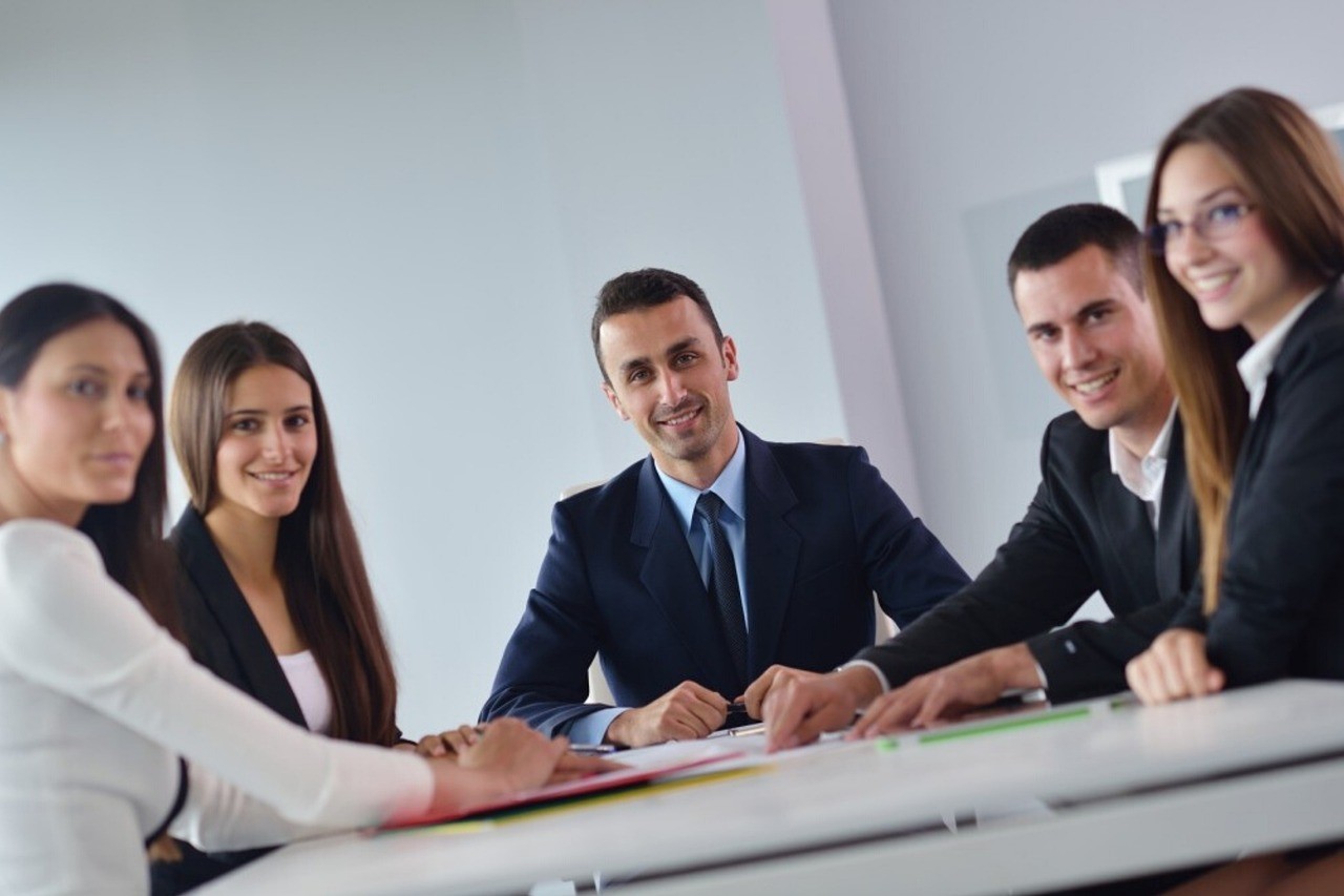 Petite équipe en discussion autour d'une table de bureau, ordinateurs ouverts