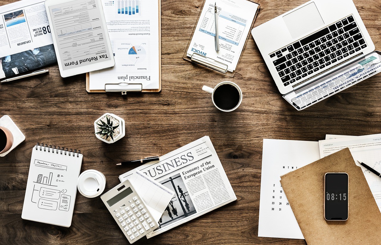 reviewing ad spend business desk Desk with financial documents, a laptop, and a calculator, representing a business reviewing its advertising spend